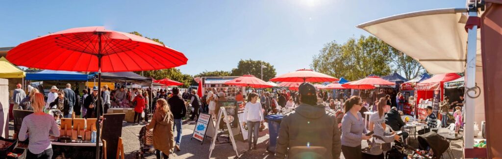 Dog-friendly Powerhouse Farmers Markets in Brisbane with stalls, umbrellas, and people enjoying the riverside setting